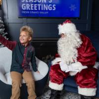 Boy points sitting next to Santa